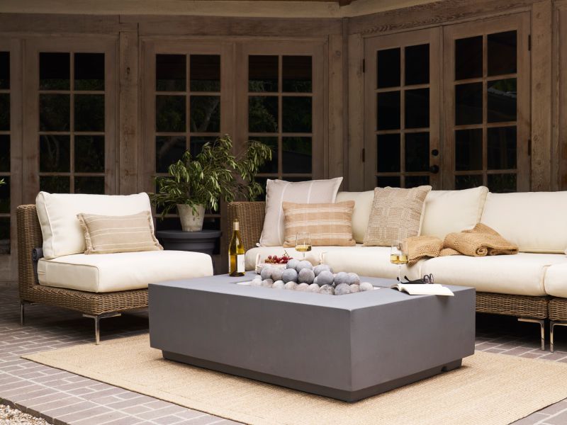 Outdoor space decorated with Outer's All-Weather Wicker Sofa and Armless Chair, surrounding Outer's Fire Pit Table